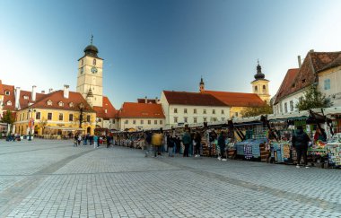 Sibiu, Romania - October 20, 2024: Small square trade kiosks. The Council Tower in the background. clipart