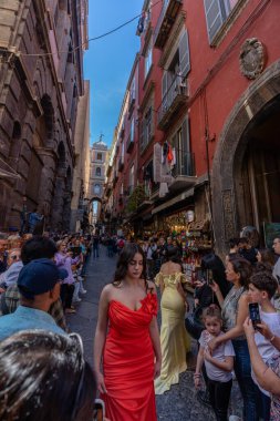 Naples, Italy - May 23, 2024: Model in a Red Dress Walking Through the Crowd at a Fashion Show. clipart