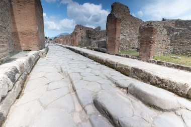 Pompei, İtalya - 25 Mayıs 2024: Pompei 'de eski taş kaldırımlar, kısmen el değmemiş binalar ve bir zamanlar gelişen ticaretin kalıntıları ile kaplı bir sokak.