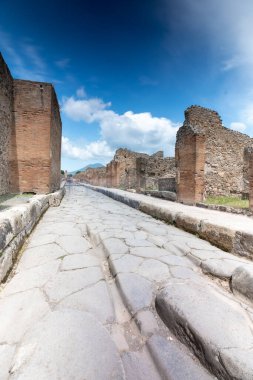 Pompei, İtalya - 25 Mayıs 2024: İtalya 'nın en ünlü arkeolojik alanlarından biri olan Pompeii' de bir sokak, antik Roma yaşamına bir bakış sunuyor. Sokaklar genellikle büyük taşlarla kaplıdır..