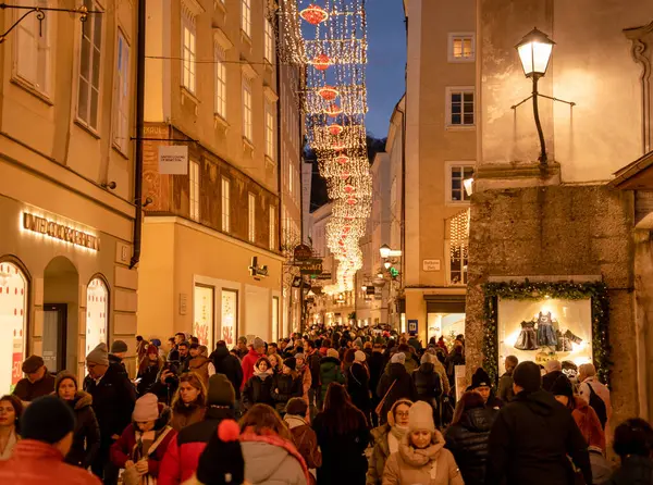 Salzburg, Avusturya - 21 Aralık 2024: Salzburg 'da akşam kalabalığı ve tatil ışıklarıyla neşeli Getreidegasse