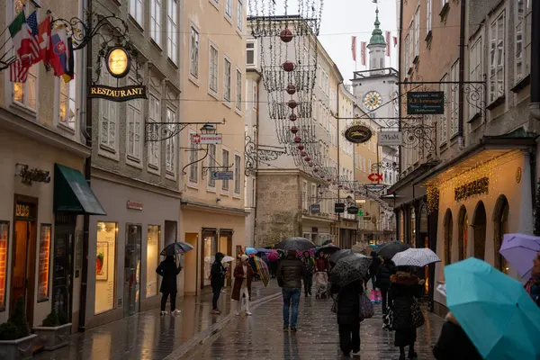 Salzburg, Avusturya - 22 Aralık 2024: Yağmurlu bir günde Noel 'de Salzburg' da Getreidegasse caddesi süslendi