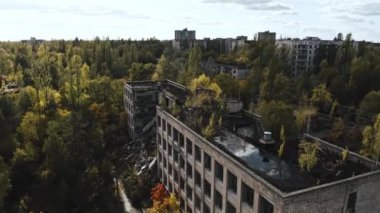 İHA, terk edilmiş Pripyat şehrinden geçiyor. Yıkılmış binalar. Şehrin aşırı gelişmiş caddeleri. Sonbahar renkleriyle Çernobil Hava Aracı Videosu - Günbatımı