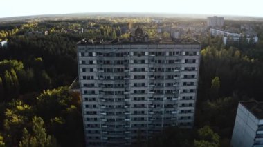 İHA, terk edilmiş Pripyat şehrinden geçiyor. Yıkılmış binalar. Şehrin aşırı gelişmiş caddeleri. Sonbahar renkleriyle Çernobil Hava Aracı Videosu - Günbatımı