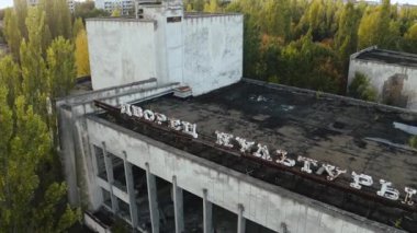 İHA, terk edilmiş Pripyat şehrinden geçiyor. Yıkılmış binalar. Şehrin aşırı gelişmiş caddeleri. Sonbahar renkleriyle Çernobil Hava Aracı Videosu - Günbatımı