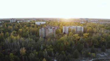 İHA, terk edilmiş Pripyat şehrinden geçiyor. Yıkılmış binalar. Şehrin aşırı gelişmiş caddeleri. Sonbahar renkleriyle Çernobil Hava Aracı Videosu - Günbatımı