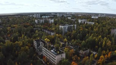 İHA, terk edilmiş Pripyat şehrinden geçiyor. Yıkılmış binalar. Şehrin aşırı gelişmiş caddeleri. Sonbahar renkleriyle Çernobil Hava Aracı Videosu - Günbatımı