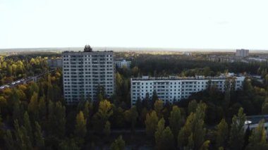 İHA, terk edilmiş Pripyat şehrinden geçiyor. Yıkılmış binalar. Şehrin aşırı gelişmiş caddeleri. Sonbahar renkleriyle Çernobil Hava Aracı Videosu - Günbatımı
