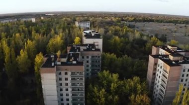 İHA, terk edilmiş Pripyat şehrinden geçiyor. Yıkılmış binalar. Şehrin aşırı gelişmiş caddeleri. Sonbahar renkleriyle Çernobil Hava Aracı Videosu - Günbatımı