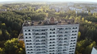 İHA, terk edilmiş Pripyat şehrinden geçiyor. Yıkılmış binalar. Şehrin aşırı gelişmiş caddeleri. Sonbahar renkleriyle Çernobil Hava Aracı Videosu - Günbatımı
