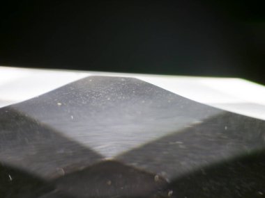 Saydam bir kristal ya da cam objenin yüzeyini gösteren soyut bir makro fotoğraf. Görüntü geometri, yansımalar ve aydınlık oyun üzerine odaklanarak hem açık hem de karanlık alanları göstermektedir. Benzersiz bulanık perspektif ve ışık saçılması