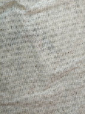 Makro fotoğraf bej çuval bezi kumaşının kabaca dokunmuş dokusunu gösteriyor. Ayrıntılı görünüm dokumadaki organik lifleri ve doğal kusurları vurguluyor, bu da onu arka plan, zanaat projeleri veya kırsal tasarım unsurları için ideal kılıyor..