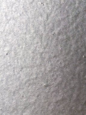 Yakın çekim makro fotoğraf kabataslak gri bir kağıdın dokulu yüzeyini gösteriyor. Görüntü, arka plan veya tasarım elementleri için ideal organik düzensizlikleri, ince lifleri ve doğal materyal kalıplarını vurgular.