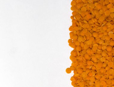 Pişmemiş turuncu mercimeği temiz beyaz arka planda yakın plan görüntüsü. Canlı turuncu renkler ve yuvarlak mercimek şekilleri, bu görüntüyü besin, beslenme ve sağlıklı beslenmeye uygun hale getiren çekici bir kontrastlık yaratır.