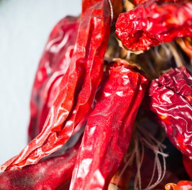 Buruşuk dokularını ve yoğun renklerini gösteren kırmızı biberlerin Macro fotoğrafı. Biberler, doğal ayrıntılarını ve parlak yüzeylerini vurgulayarak bir araya getiriliyor. Mutfak ve baharatla ilgili konular için ideal..