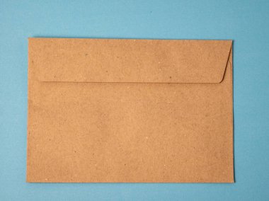 A brown kraft paper envelope is placed on a flat blue background, viewed from above. The envelope is closed and unaddressed, making it ideal for themes related to mail, stationery, correspondence, or invitations.