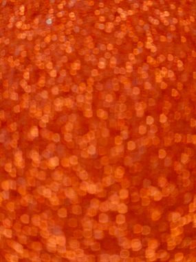 Out of focus abstract image featuring a vibrant orange bokeh effect, creating a shimmering and festive background. Suitable for use in design, celebration, holiday, or party themes requiring a warm, glowing, and energetic backdrop.
