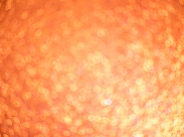 Abstract photograph featuring a soft, warm orange and gold bokeh background with multiple defocused circular light spots. The glowing pattern creates a festive, celebratory atmosphere suitable for a variety of creative and commercial designs.