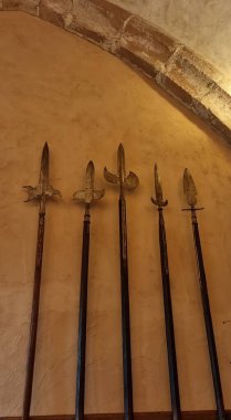 Vianden, Luxembourg - May 03, 2024: Medieval long shaft polearms with various metal heads mounted on a wall and used as room decoration clipart