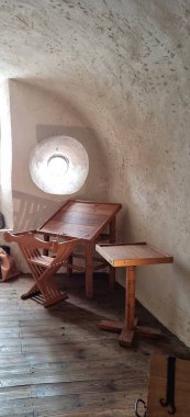 Vianden, Lüksemburg - 3 Mayıs 2024: Kemerli tavanlı küçük bir odanın iç tasarımı, duvarda havalandırma penceresi, ahşap mobilyalar ve tahta döşemeler.