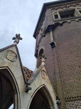 S-Hertogenbosch, Netherland - May 08, 2024: Part of Heeswijk Castle decorated with red bricks, gabled roofs, decorative mullions windows, many decorative elements on the facade and black iron fence clipart