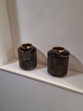 Haarlem, Hollanda - 14 Mayıs 2024: İki silindirik, koyu renk ve dekoratif depolama ve süs eşyası olarak kullanılan beyaz bir rafta duran dekoratif kapların boyutları ve tasarımı aynı.