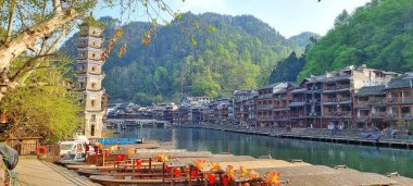 Zhangjiajie, Çin - 2007, 2025: Fenghuang Antik Kenti 'ndeki çok katlı pagoda kulesinin önde gelen geleneksel Çin mimarisi geleneksel stilt evler, renkli tekneler ve deniz manzarası