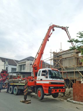 Bandung, Endonezya - 3 Mayıs 2025: İnşaat alanına sıvı beton pompalamak için uzun eklemli kollu büyük beton pompa kamyonu yukarı doğru genişletilir