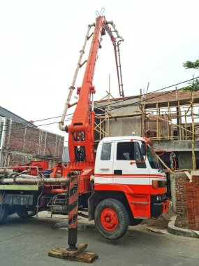 Bandung, Endonezya - 3 Mayıs 2025: İnşaat alanına sıvı beton pompalamak için uzun eklemli kollu büyük beton pompa kamyonu yukarı doğru genişletilir