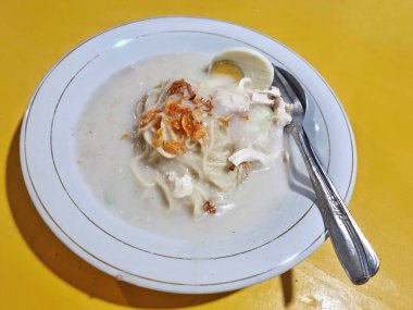 Cirebon, Endonezya - 11 Mayıs 2025: Bir tabak geleneksel Cirebonese yemeği kremsi beyaz et suyunda erişte, tavuk parçaları, haşlanmış yumurta ve serpilmiş kızarmış arpacık soğanı