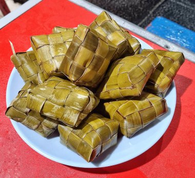 Jakarta, Endonezya - 18 Mayıs 2025: Beyaz bir tabakta ketupat olarak bilinen pirinç dolu elmas şeklinde örülmüş palmiye yapraklarından pişirilmiş