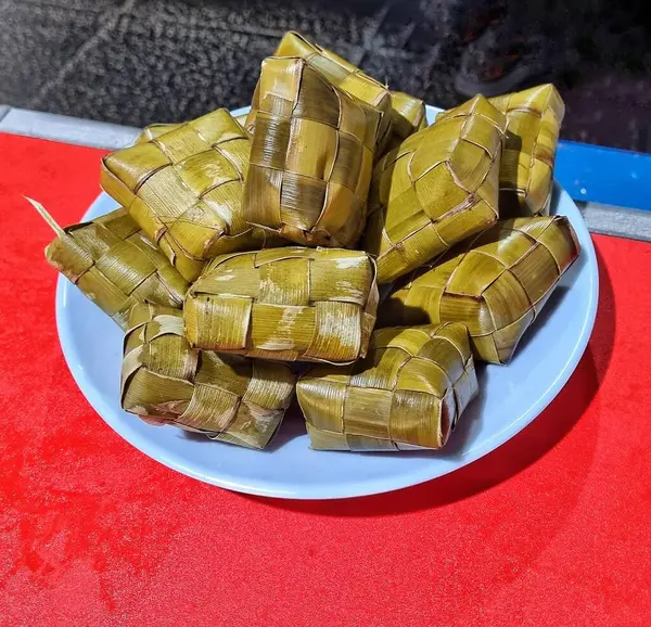 Jakarta, Endonezya - 18 Mayıs 2025: Beyaz bir tabakta ketupat olarak bilinen pirinç dolu elmas şeklinde örülmüş palmiye yapraklarından pişirilmiş