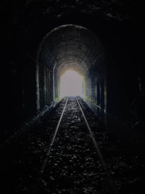 4.2 kilometre uzunluğunda eski bir tünelden geçen insanların siluetinin fotoğrafı.