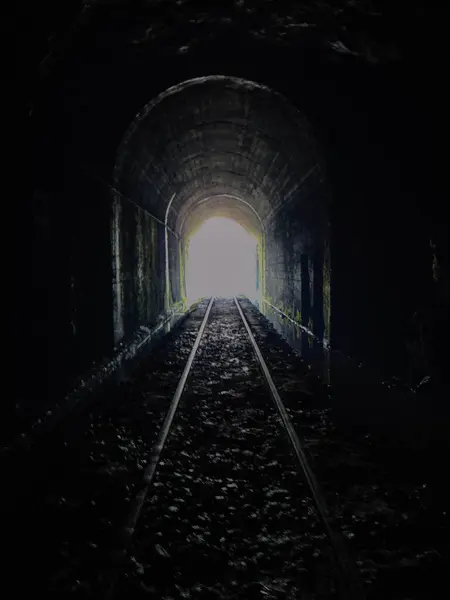 Photograph of the silhouette of people crossing an old tunnel 4.2 kilometers long
