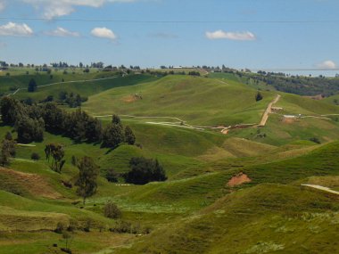 Manzarayı tamamlamak için dağları olan manzara, farklı tonlarda yeşil dağlar, arka planda bulutlar ve mavi bir gökyüzü..