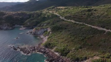 Sardunya kıyı şeridinin atmosferik görüntüsü berrak mavi su ve gün batımında bir sahil yolu.