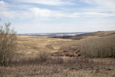 Üzerinde mavi bir gökyüzü olan geniş, açık bir alan. Gökyüzü bulutlu ve alanda barışçıl ve geniş bir doğal manzara yaratan görünür binalar ya da yapılar yok..