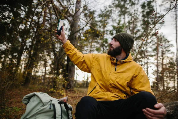 Brodaty Człowiek Spoczywa Upadłym Drzewie Środku Lasu Mężczyzna Używa Telefonu — Zdjęcie stockowe