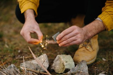 Bir adam bir flint ile ateş yapar