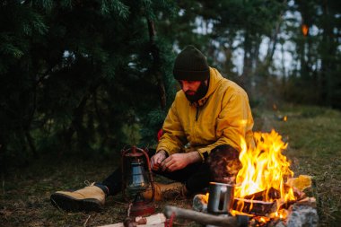 The traveler uses a kerosene lamp. Setting up a shelter in the forest for the night. clipart