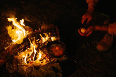 Bir gezgin şenlik ateşinde kızarmış yumurta pişirir. Vahşi doğada seyahat ve hayatta kalma kavramı..