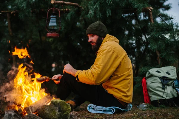 Bearded Male Hiker Roasts Sausages Bonfire Dinner Wild Travel Survival — Stock Photo, Image