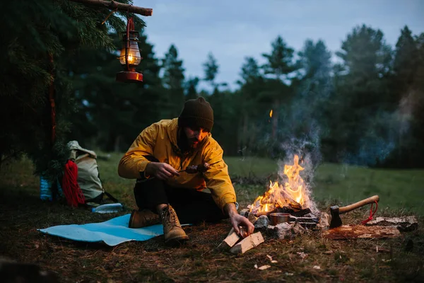 孤独な放浪者がキャンプファイヤーで山の中で夕食を取っている — ストック写真