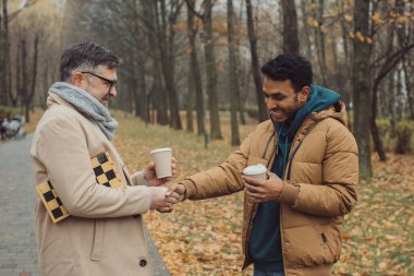 Arkadaşlar, bir son sınıf öğrencisi ve genç bir adam sonbahar parkında birlikte yürüyor, konuşuyor ve kahve içiyor.
