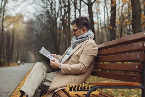 Egy Idős Férfi Újságot Olvas Miközben Egy Padon Egy Őszi — Stock Fotó