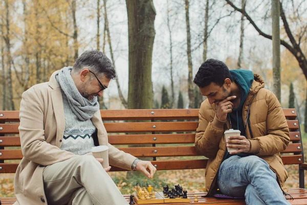 Φίλοι Παίζουν Σκάκι Ένα Παγκάκι Ένα Πάρκο Φθινόπωρο Πολυπολιτισμική Φιλία — Φωτογραφία Αρχείου