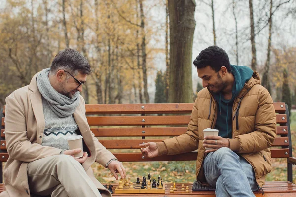 在秋天公园的长椅上下棋的多种族男人 — 图库照片
