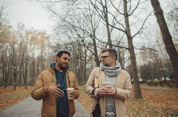 Przyjaciele Starszy Młody Mężczyzna Spacerujący Rozmawiający Pijący Kawę Jesiennym Parku — Zdjęcie stockowe