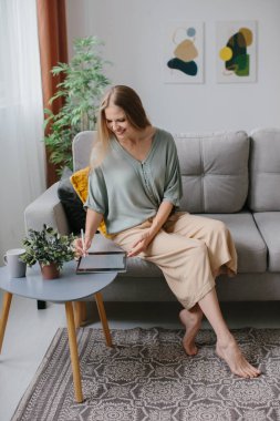 Kanepede bir tablet ve stil ile oturan bir kız.