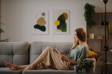 Güzel sarışın genç kadın çizer evdeki tablete..